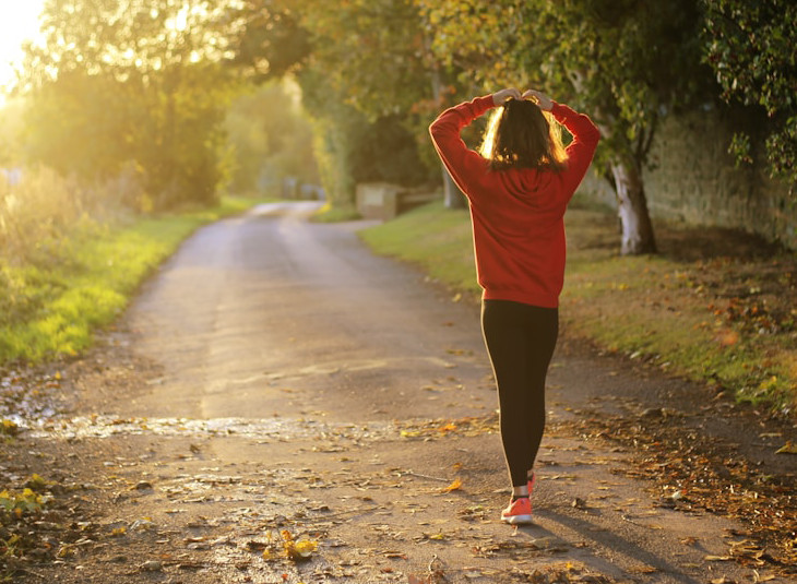 lady walking along a path in the country towards the sun